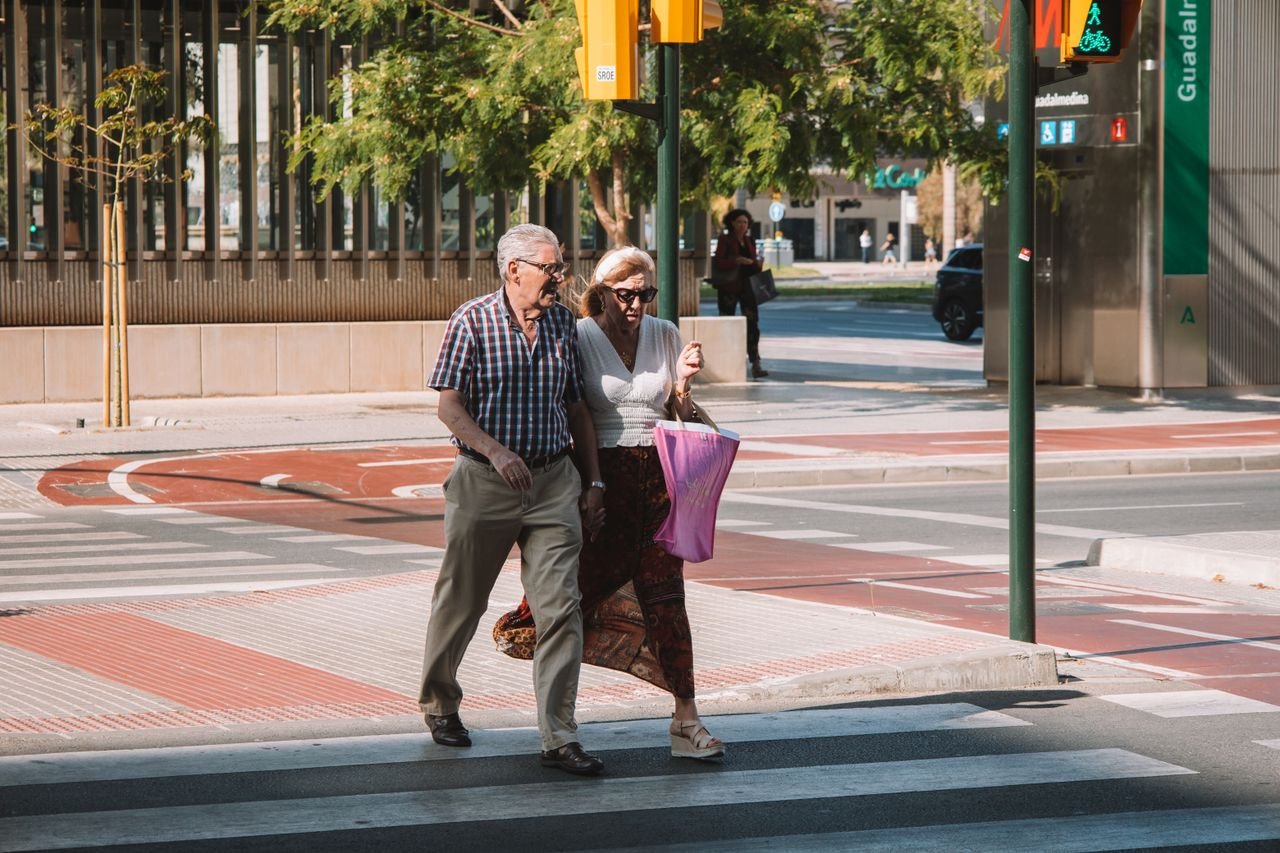 Senior couple crossing street in Málaga, Spain on a sunny day.