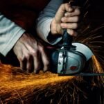 A worker skillfully operating an electric grinder, producing dynamic sparks.